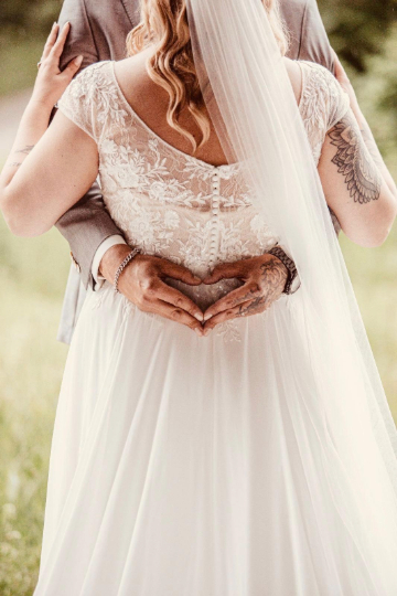 Paar bei der Hochzeit zeigt Herzgeste als Ausdruck ihrer Erfahrung einer besonderen freien Trauung