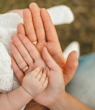 Familienfotografie - Eltern halten die Hand vom Baby - Essence of Love gestaltet emotionale Willkommensfeiern für Babys