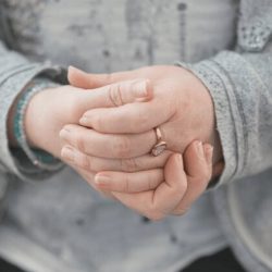 Eine Person hält liebevoll ihre eigenen Hände – ein bewusster Augenblick der Verbindung mit sich selbst, fotografisch begleitet von Essence of Love